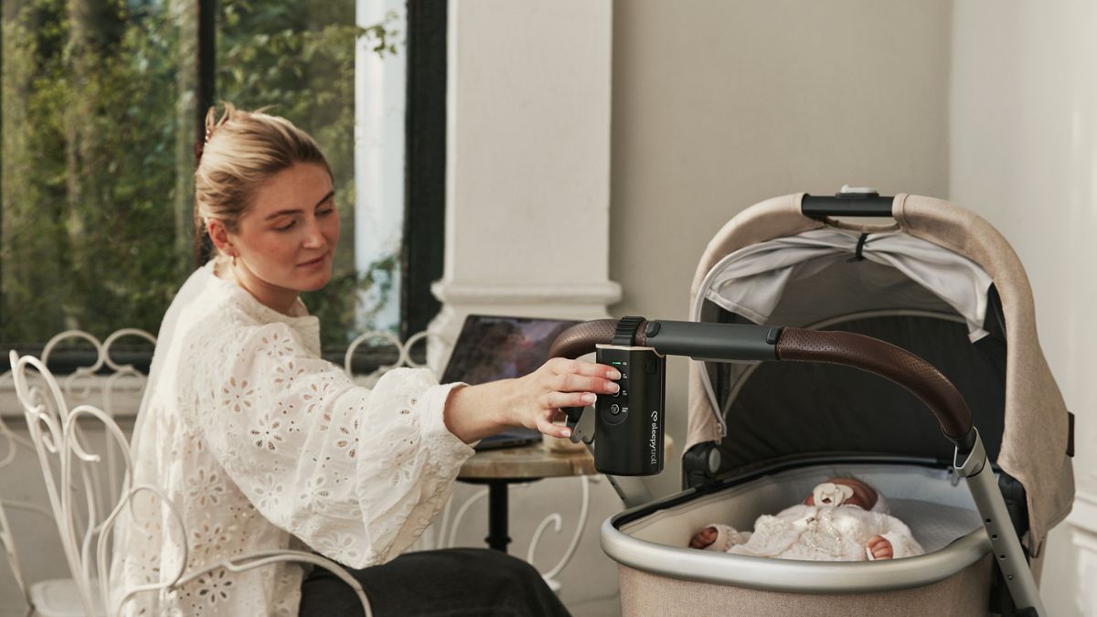 Baby sleeping outdoors in bassinet rocked by Sleepytroll Stroller Rocker so mom can get some work done.